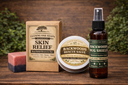 A set of natural soaps and bug spray from Leaning Oak Soaps, including a Skin Relief dual relief bar, a Backwoods Rescue Salve tin, and a Backwoods Bug Shield spray bottle, arranged on a rustic wooden surface with a blurred green foliage background.